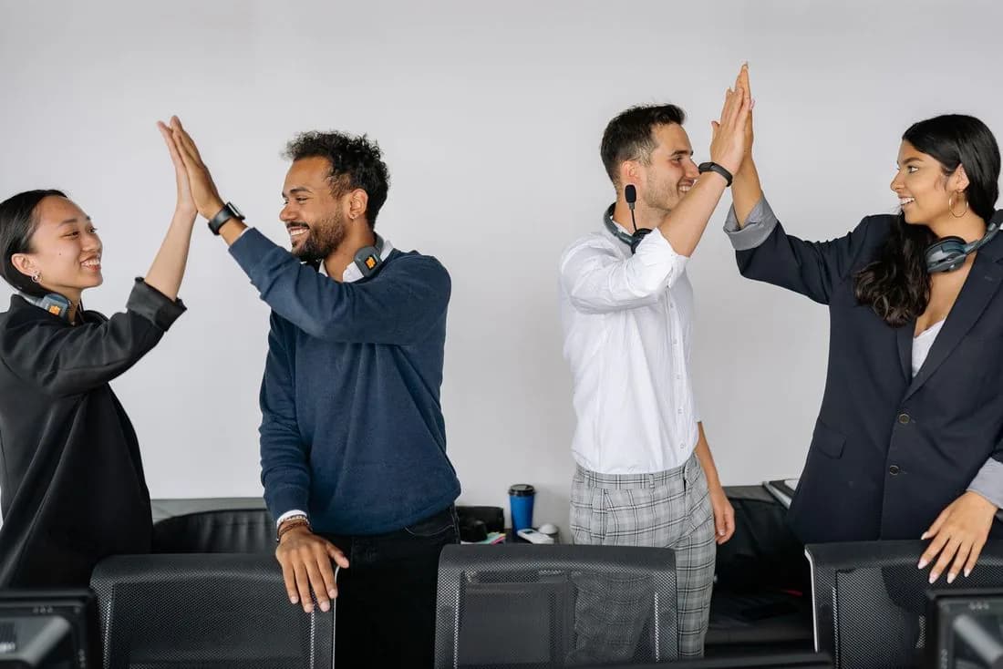 Support team giving high fives at their desks