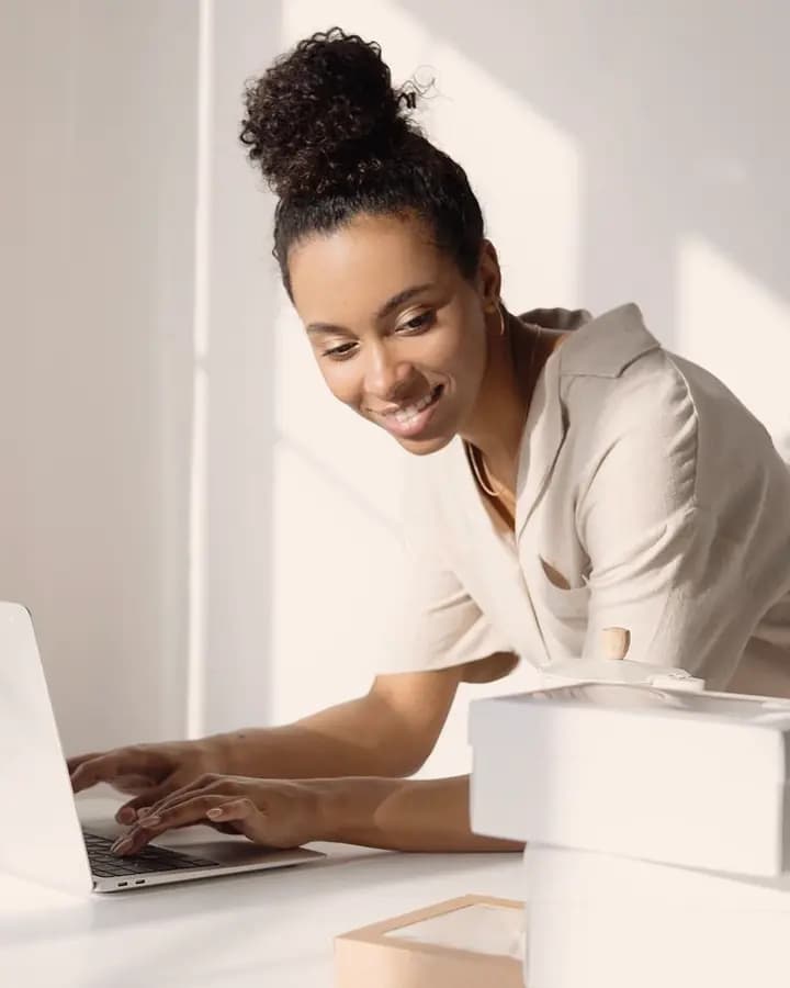 Seller smiling at her laptop beside packed orders